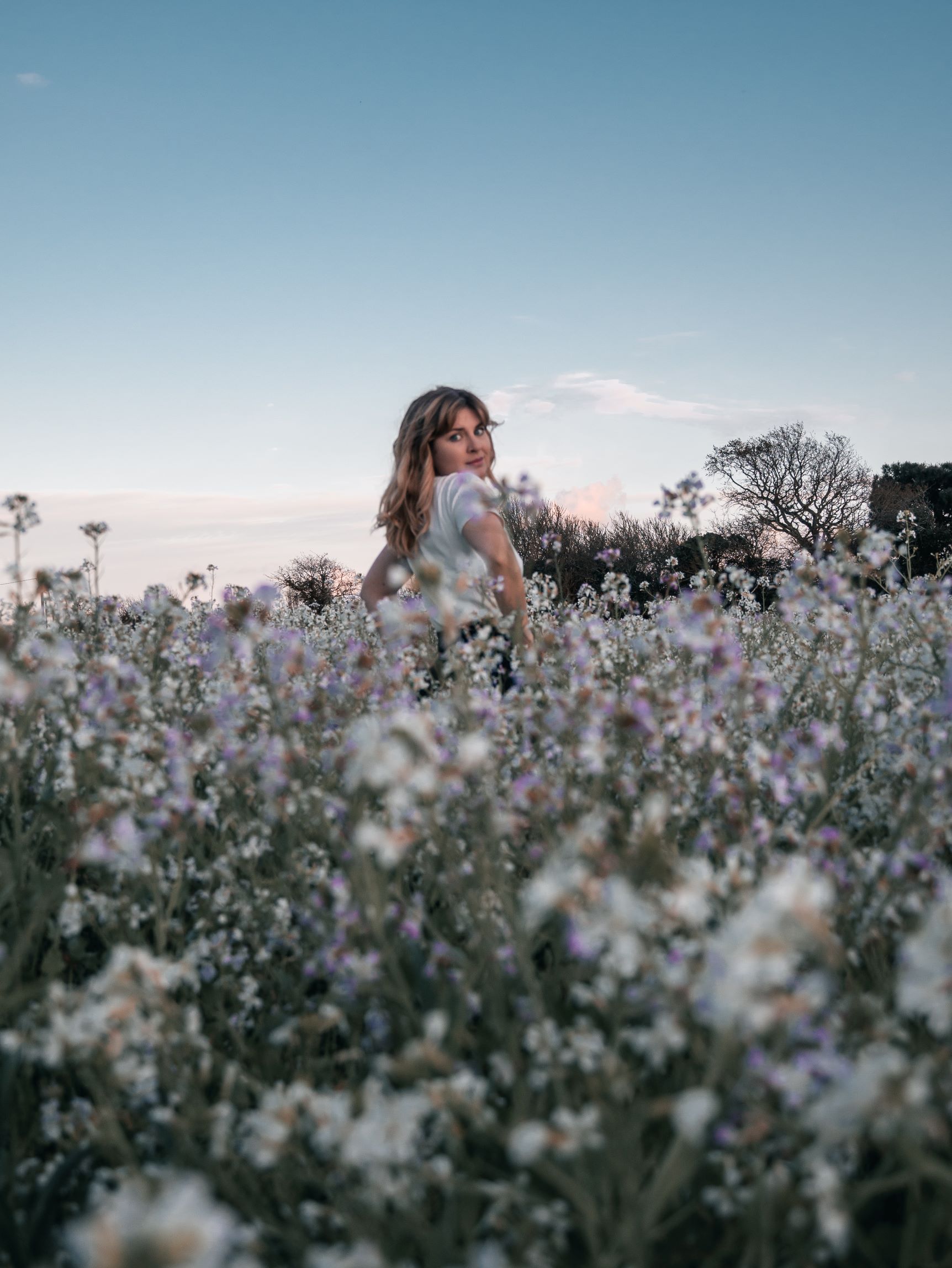 océane naturopathe spécialisée dans l'endométriose, dans un champ de fleurs blanches et lilas